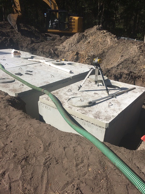 Concrete septic tank lowered into an excavation.