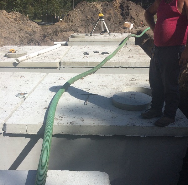 Concrete septic tank with pipe and hose connected during installation.