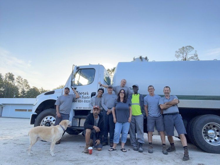 Members of the Moore's Sand and Septic team standing beside a company truck.